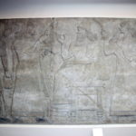 王の祝い　椅子に座った王が杯を持ち、祝杯をあげようとしている。前後の従臣は蝿叩きを持っている