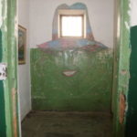 元監獄　窓が帽子、緑の壁に、赤い唇の女が描かれているド派手な房。横の壁に住人？が描かれている