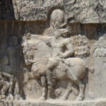 ナグシェ・ロスタム　ササン朝時代のレリーフ、騎馬戦勝図。シャプール1世の馬前に跪いているのは捕虜となったローマ皇帝ヴァレリアヌス